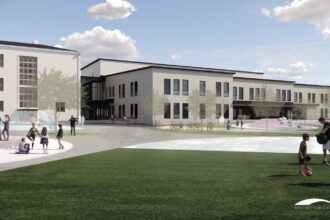 Visualisation from the schoolyard: the renovated three-storey 1939 stone school on the left, joined to the new dark-roofed daycare wing, with children playing on the lawn.