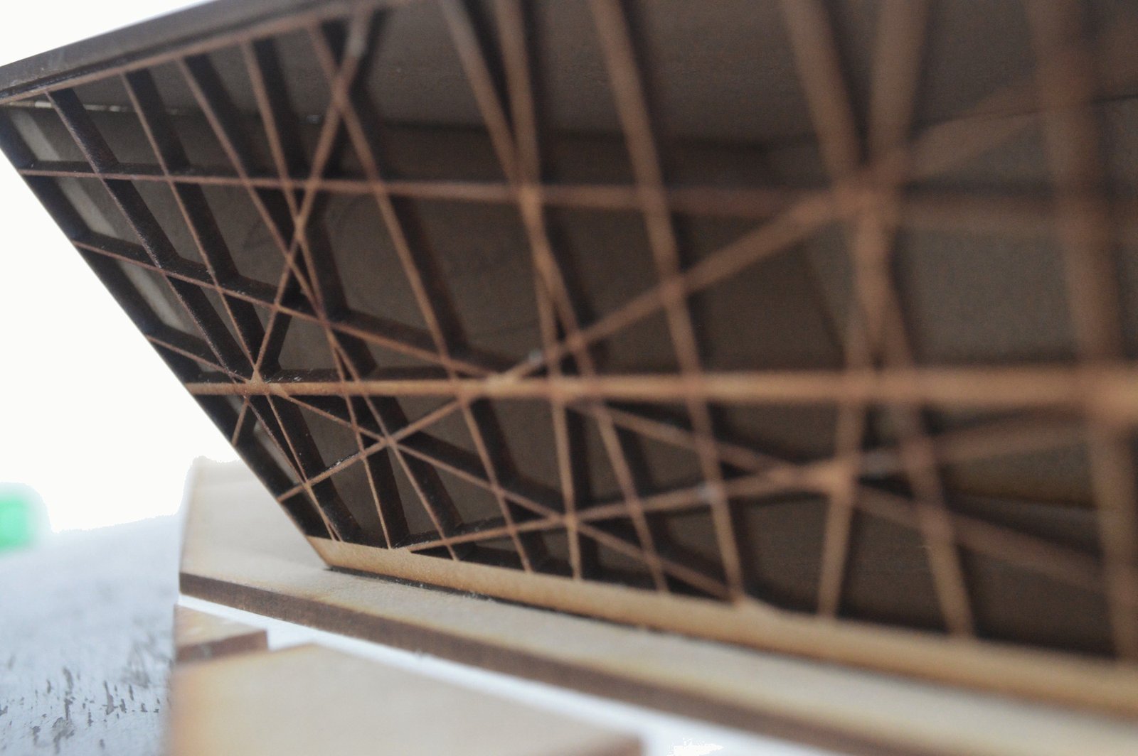 Close-up of the model’s lattice façade: crossing diagonal fins casting layered shadows.